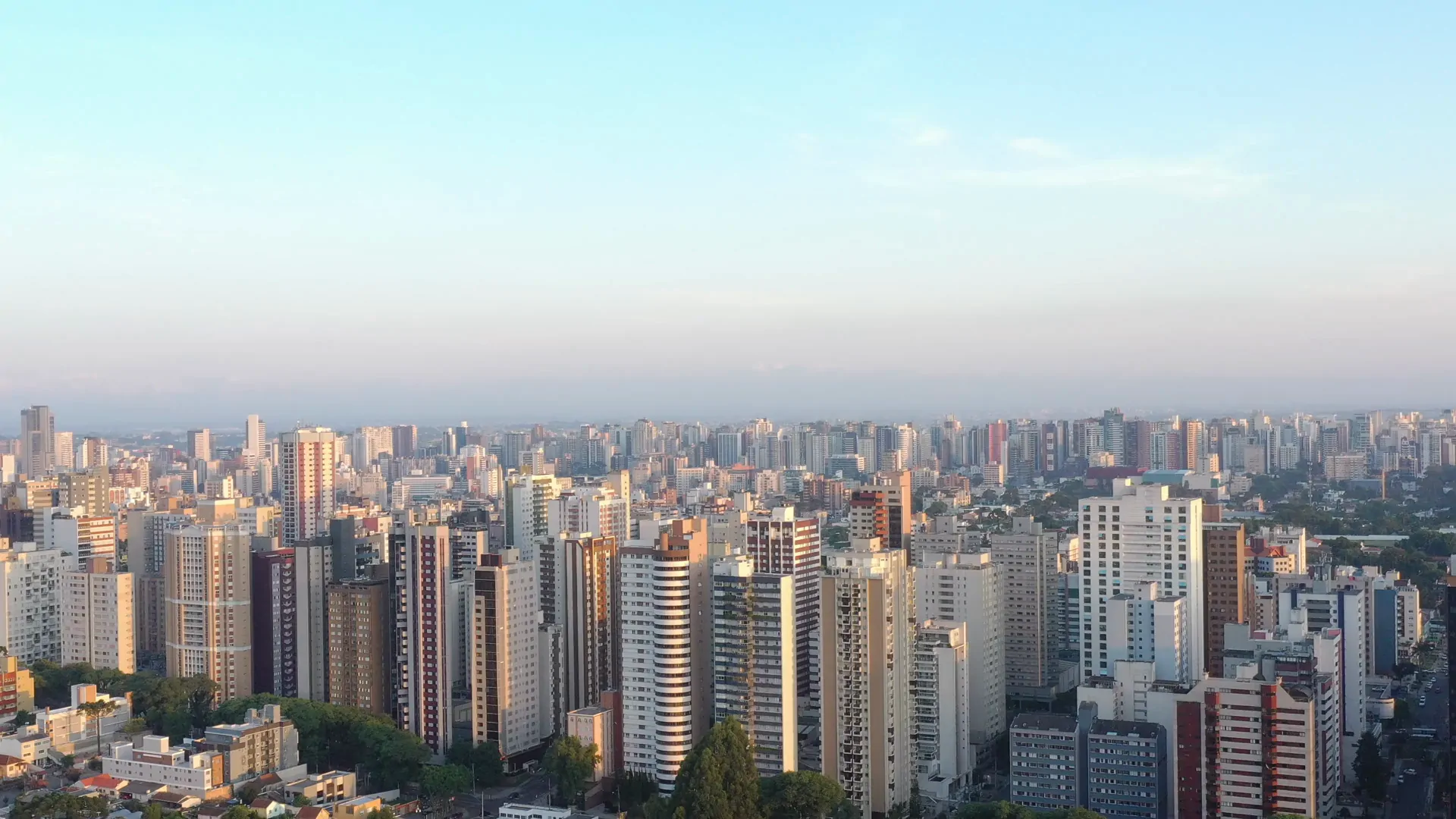 Skyline de Curitiba ao entardecer, prédios residenciais e comerciais em primeiro plano